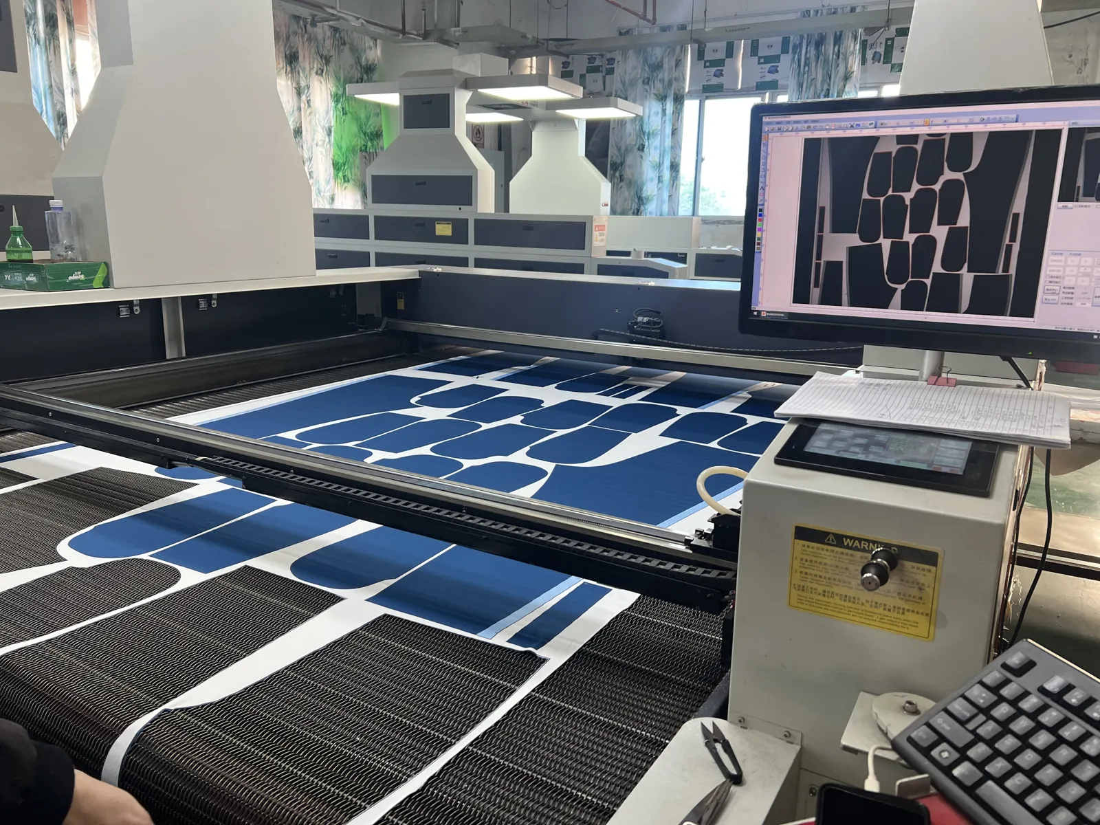 Laser cutting machine cutting sublimated fabric panels at the Eliian factory in Xiamen